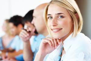 Closeup of a pretty young businesswoman smiling in a meeting with her colleagues in background